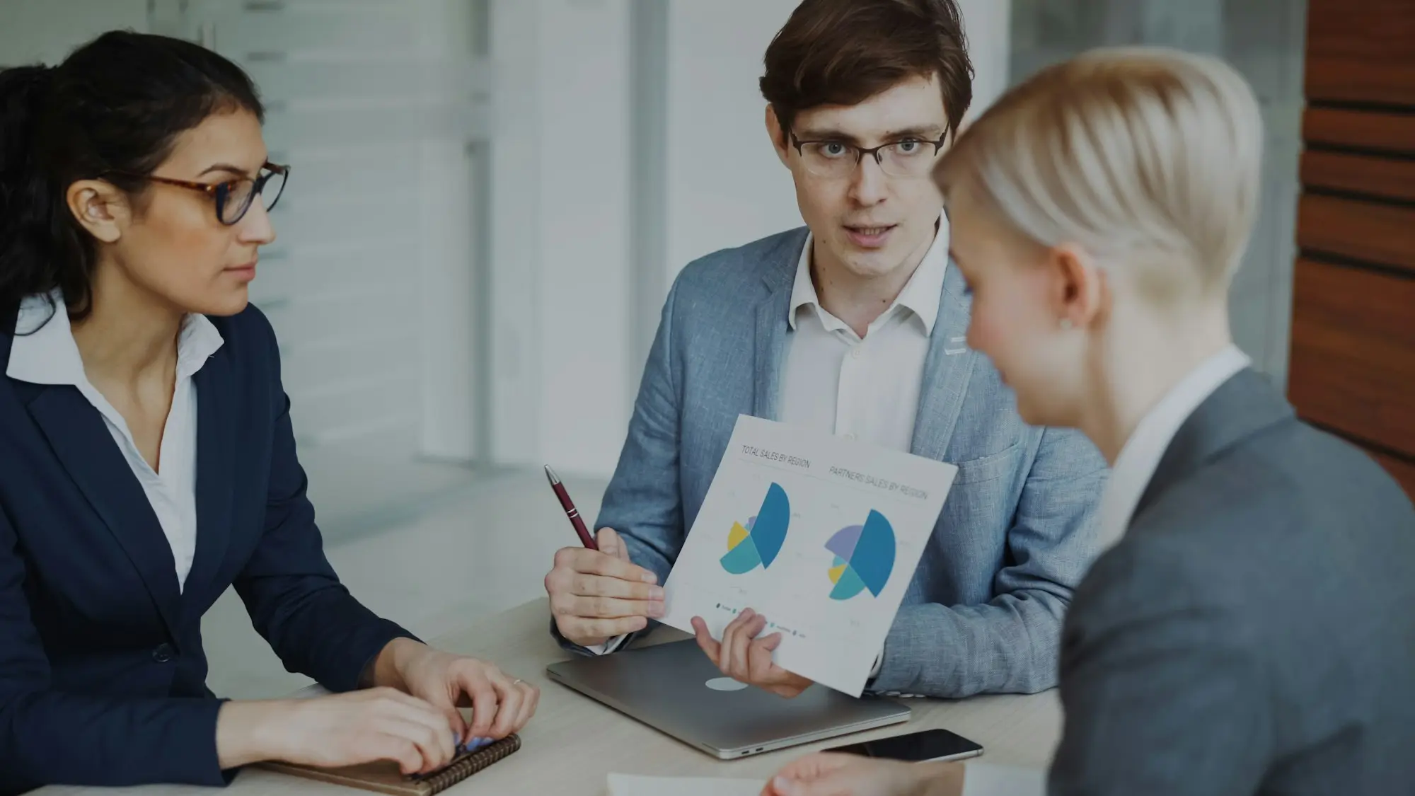 Three professionals discussing charts in a meeting