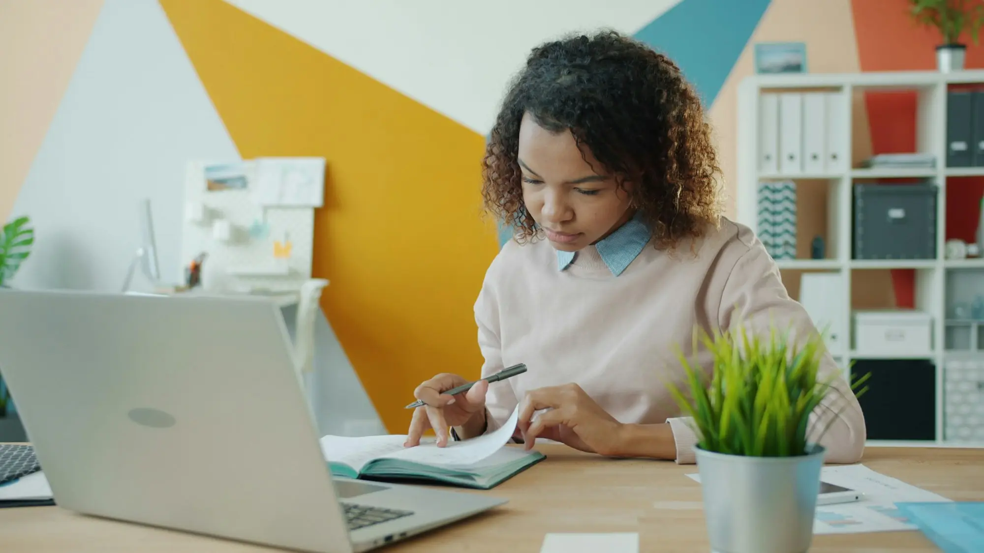 Business owner working through provisional tax figures with a notebook and laptop at her office desk